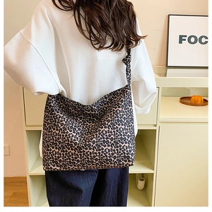 Model wearing a large leopard print hobo tote bag in a minimalist lifestyle setting
