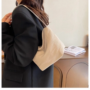 Détail du sac à bandoulière plissé crème montrant la texture souple et la bandoulière