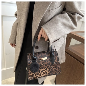 Détail du sac cabas léopard avec poignées rondes noires et accents dorés en métal