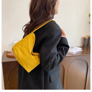 Détail du sac à bandoulière plissé jaune en nylon souple porté par un mannequin femme