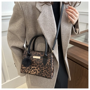 Détail du sac à main léopard avec boucle dorée et accessoire pompon en fourrure noire