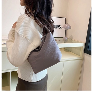 Détail du sac à bandoulière gris foncé en tissu plissé montrant le drapé sur un modèle