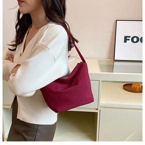 Détail du sac hobo bordeaux en daim doux porté à l'épaule pour un look chic et élégant