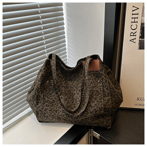 Detail of leopard print tote bag with front pocket, metal rivets and leather patch label