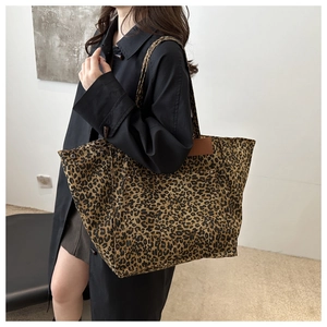 Detail of leopard print tote bag with brown leather patch and metal rivet accents