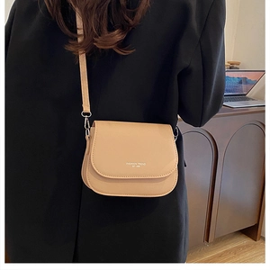 Side view of beige saddle bag on model featuring Fashion Trend Est 1996 text print