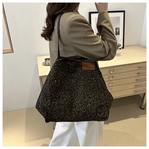 Detail of a large leopard print tote bag with an outer pocket shown in a stylish room