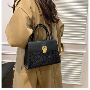 Close-up of crocodile texture handbag with gold buckle shown on a trench coat model