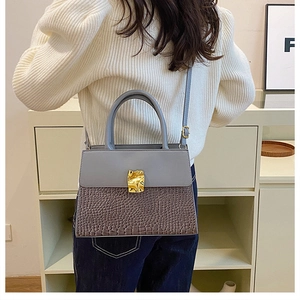 Détail du sac à main bleu-gris à texture crocodile et boucle dorée sur un mannequin
