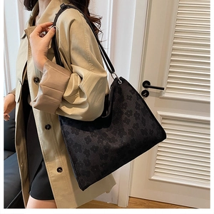 Sac cabas noir à motif floral et anneaux argentés porté par un mannequin