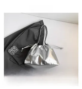 Detail of silver metallic drawstring bucket bag with bow on grey blazer background