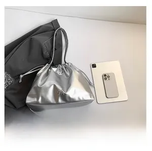 Top view of silver drawstring bucket bag with metallic bow charm and casual accessories