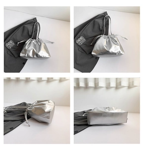 Detail of silver metallic drawstring bucket bag with bow emblem and thin shoulder strap