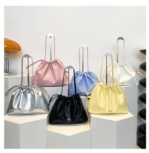 Close-up of multi-color drawstring tote bags with metallic bow detail on geometric stands