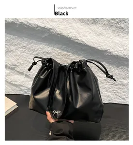 Close-up of black pleated bucket bag with a delicate silver bow and drawstring detail