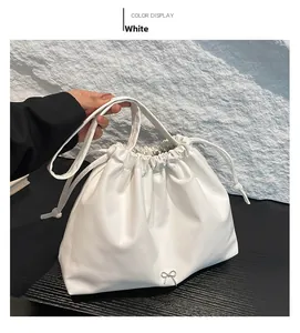 Detail showing white ruched drawstring bag with a silver metal bow and soft texture