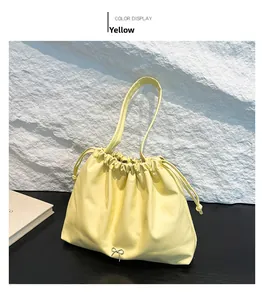 Close-up of pale yellow leather handbag with drawstring closure and metal butterfly charm