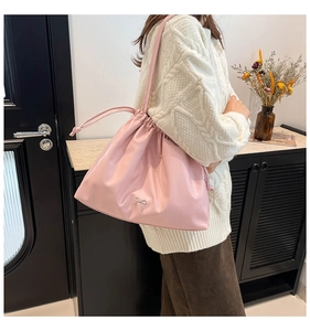 Detail of drawstring tote bag in light pink with metal bow ornament and pleated design
