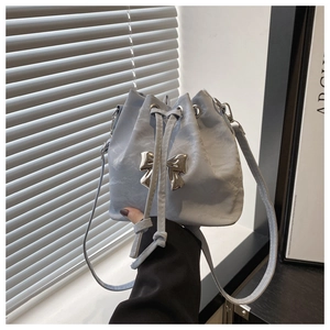 Close-up of sky blue drawstring bucket bag featuring a silver metal bow and wrinkled texture