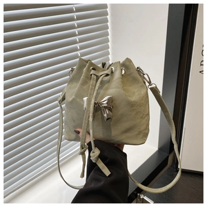 Detail of light green drawstring bucket bag with silver bow ornament and soft texture