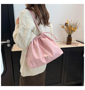 Detail of pink drawstring bucket bag with silver bow accent and soft pleated texture