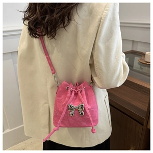 Pink drawstring bucket bag with silver bow detail worn by a model in casual style