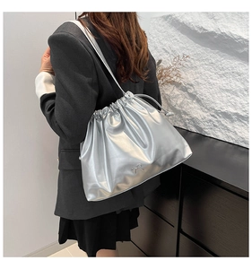 Detail of silver metallic pleated bucket bag with bow buckle decoration on a shoulder