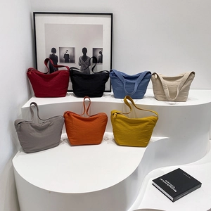 Sacs à bandoulière plissés minimalistes en sept couleurs vives sur des marches blanches