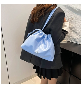 Detail of light blue pleated bucket bag with silver metal bow and drawstring closure