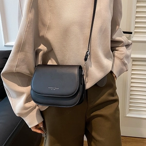 Chic black saddle shoulder bag in faux leather with white typography for women
