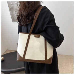 Minimalist bicolor tote bag with brown leather trim shown in a side-view lifestyle shot