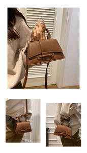 Detail of dark brown lychee leather handbag with ring buckle and thin crossbody strap