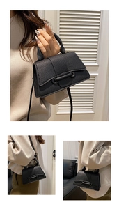 Close-up of black litchi grain leather handbag with stylish metal bar buckle detail