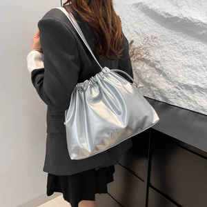 Silver pleated drawstring bucket bag with metallic bow detail for women on shoulder