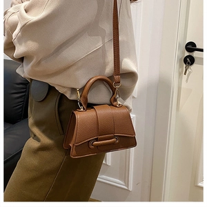 Brown litchi grain trapezoid handbag with curved base and gold hardware on model