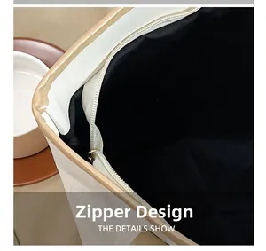 Dettaglio della chiusura a zip di una borsa tote beige con finiture in metallo lucido