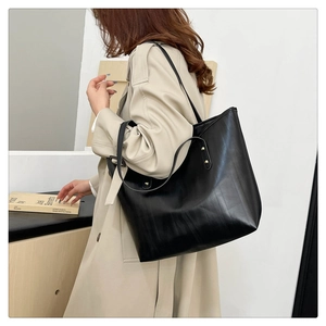 Foto lifestyle di una grande borsa tote nera in ecopelle con rivetti dorati per il lavoro