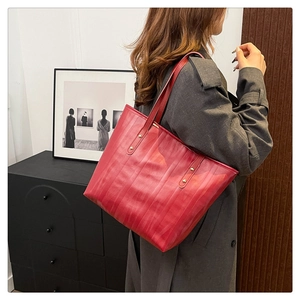 Dettaglio borsa tote rossa capiente con texture verticale e rivetti dorati decorativi