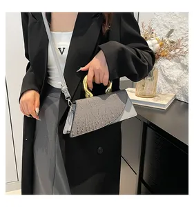 Detail of crocodile pattern leather handbag with bold golden U-shaped metal handle