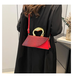 Detail of red crocodile pattern bag featuring unique heart-shaped gold metal handle