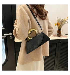 Detail of black crocodile texture leather bag with unique molten gold metal handle
