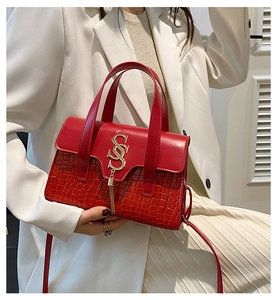 Detail of red crocodile texture handbag with gold S-buckle and elegant tassel charm