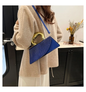 Detail of blue crocodile pattern bag with sculpted gold handle and shoulder strap