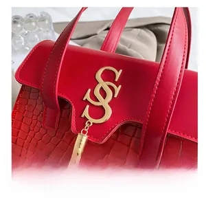 Detail shot of red handbag showing crocodile embossed leather and golden letter logo charm