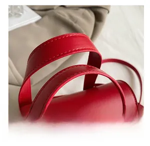 Close-up of double handles on a red crocodile pattern handbag with fine stitching details