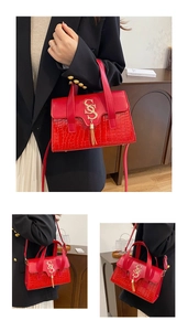 Close-up of red crocodile texture handbag with gold metal S logo and leather tassel detail