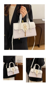 Detail of cream beige leather handbag with crocodile pattern texture and tassel gold clasp
