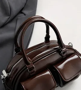 Vue détaillée des poignées de sac baguette marron brillant avec coutures et zip métal