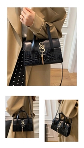 Close-up of black alligator embossed leather bag with gold SS logo and stylish tassels