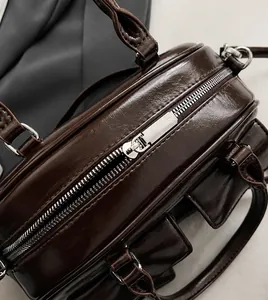 Gros plan sur la fermeture éclair en métal et la texture cuir chocolat du sac